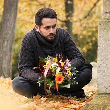 Man mourning loved one at graveyard | ajkkafe/Getty Images