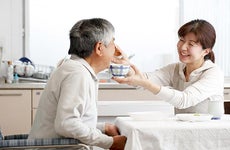Daughter feeding her father a bowl of soup © kazoka/Shutterstock.com