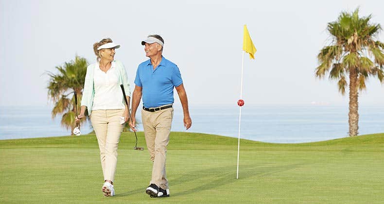 Mature couple playing golf | Chris Ryan/Getty Images