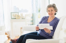 Mature woman holding bills | Tetra Images/Getty Images