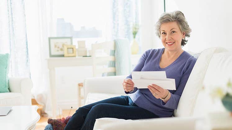 Mature woman holding bills | Tetra Images/Getty Images