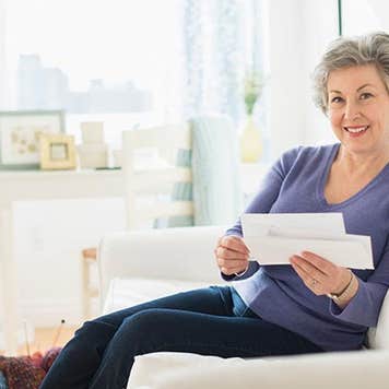 Mature woman holding bills | Tetra Images/Getty Images