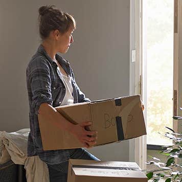 Serious woman carrying moving box | Gary Burchell/Getty Images