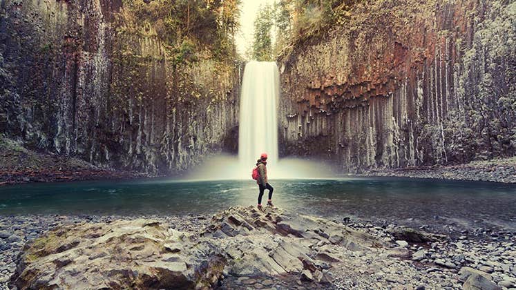 Woman standing by waterfall | Peerasith Patrick Triratpadoongphol/Shutterstock.com