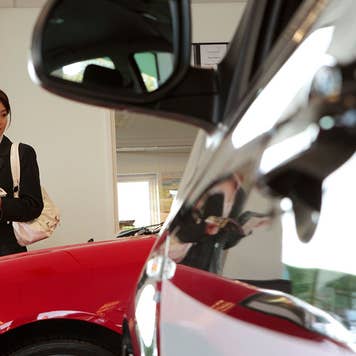 A closeup of a car with a woman in the background.