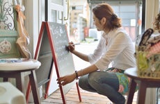 Woman in cafe writing on sign