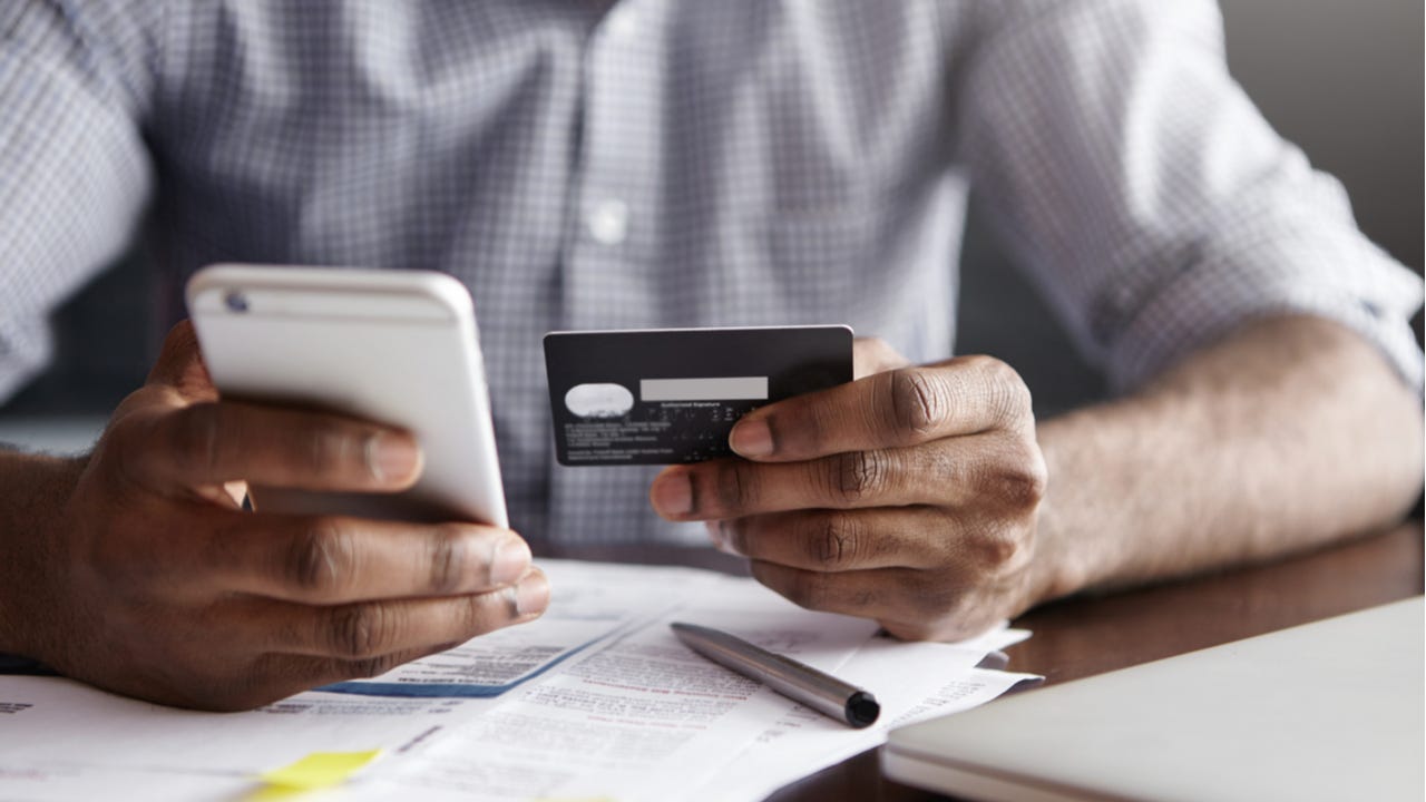 Man paying bill with credit card and phone