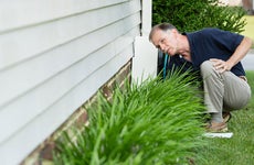 Man inspecting foundation of house