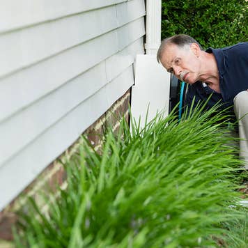 Man inspecting foundation of house
