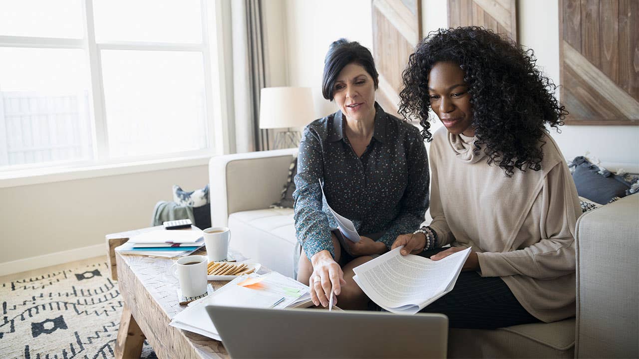 Two women look over paperwork and a computer