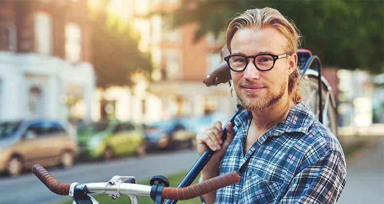 Young man in plaid shirt holding bike © Uber Images/Shutterstock.com