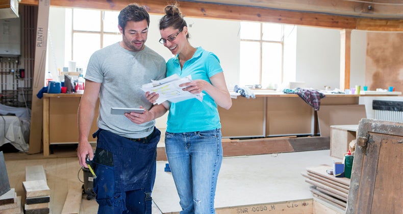 Couple standing in the middle of room being remodeled © iStock