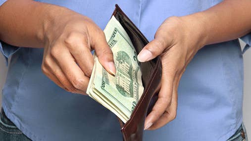 Woman in blue shirt opening wallet © PTstock/Shutterstock.com