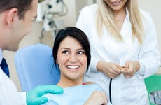Woman in dentist's chair getting cleaning | Lucky Business/Shutterstock.com
