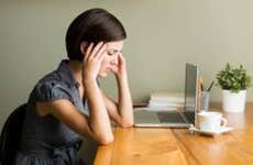 Stressed woman with a headache in home office | iStock.com/Aldo Murillo
