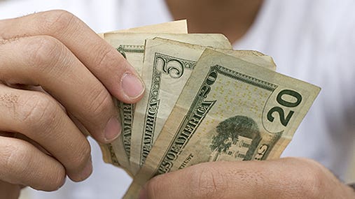 Man counting bills in hand © Jason Stitt/Shutterstock.com