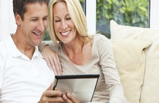Couple sitting in sofa using tablet computer © iStock