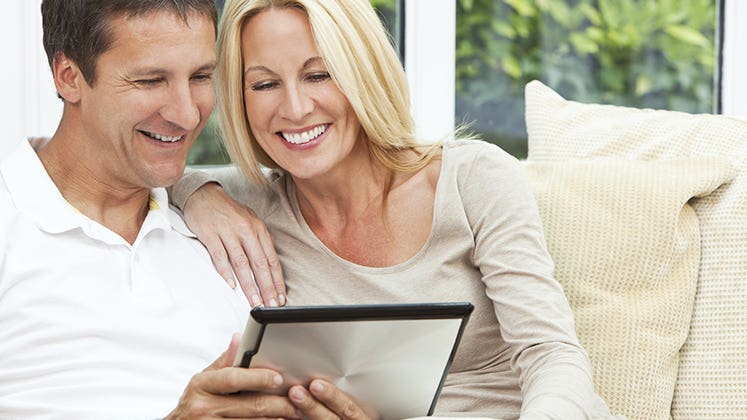 Couple sitting in sofa using tablet computer © iStock