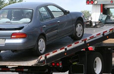 Car being lifted onto tow truck bed 