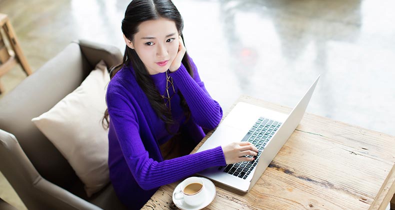 Young woman in purple sweater using laptop computer | iStock.com/visionchina