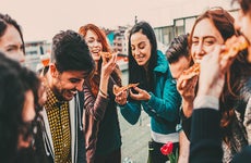 Millennials laughing and eating pizza | Todor Tsvetkov/Getty
