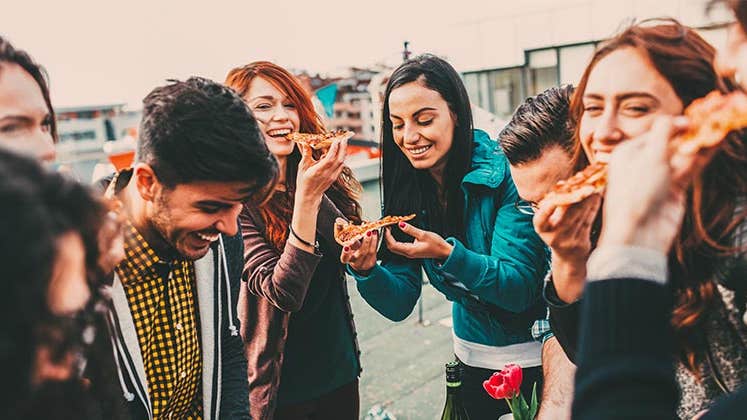 Millennials laughing and eating pizza | Todor Tsvetkov/Getty