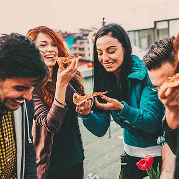 Millennials laughing and eating pizza | Todor Tsvetkov/Getty