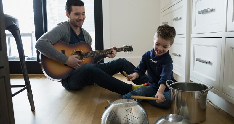 Father playing 'band' with son in kitchen | Hero Images/Getty Images