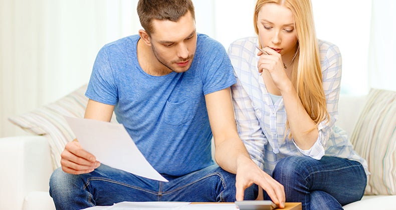 Busy couple with papers and calculator at home © Syda Productions/Shutterstock.com