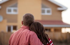 Couple standing outside looking at house © luxorphoto/Shutterstock.com