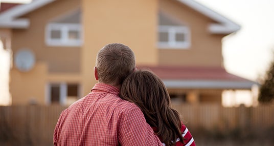 Couple standing outside looking at house © luxorphoto/Shutterstock.com
