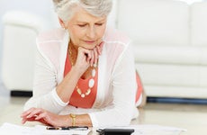 Woman using her calculator at home © iStock
