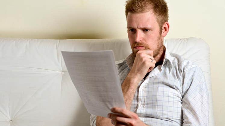 Serious young man reading paperwork © iStock