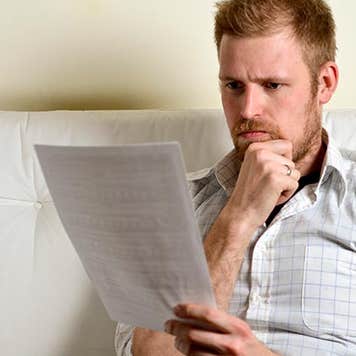 Serious young man reading paperwork © iStock