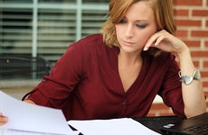 Woman writing and reading paperwork © Charlotte Purdy/Shutterstock.com
