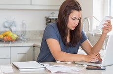 Woman holding a bill while calculating on laptop © wavebreakmedia/Shutterstock.com