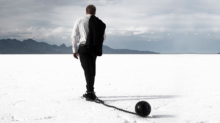Disappointed businessman dragging ball and chain © iStock