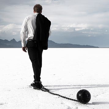 Disappointed businessman dragging ball and chain © iStock