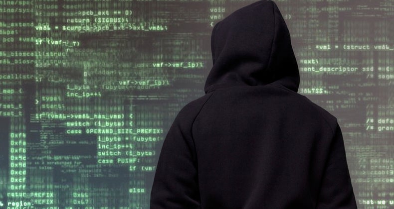 Hooded figure looking at lines of code © iStock