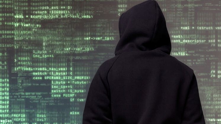 Hooded figure looking at lines of code © iStock