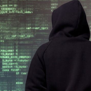 Hooded figure looking at lines of code © iStock