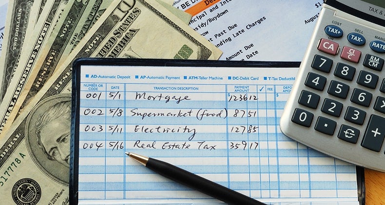 Balancing checkbook with money calculator bank statement © JohnKwan/Shutterstock.com