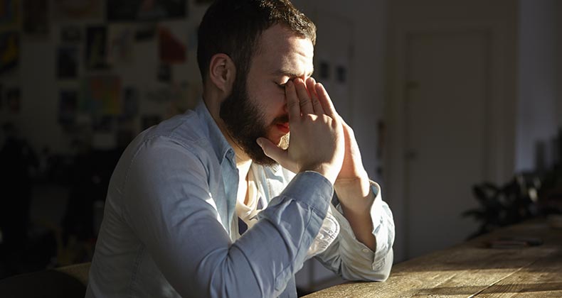 Man pinching bridge of nose | Aleli Dezmen/Getty Images