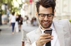 Man wearing beige suit, browsing smartphone | Kinga/Shutterstock.com