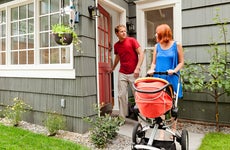 Father and mother leaving house with baby in stroller