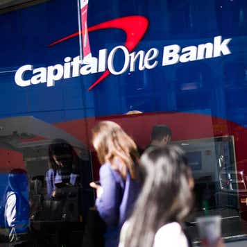 People walking back and forth in front of Capital One Bank entrance.