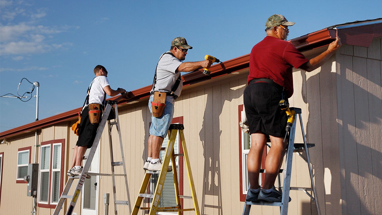 Three workers installing gutters