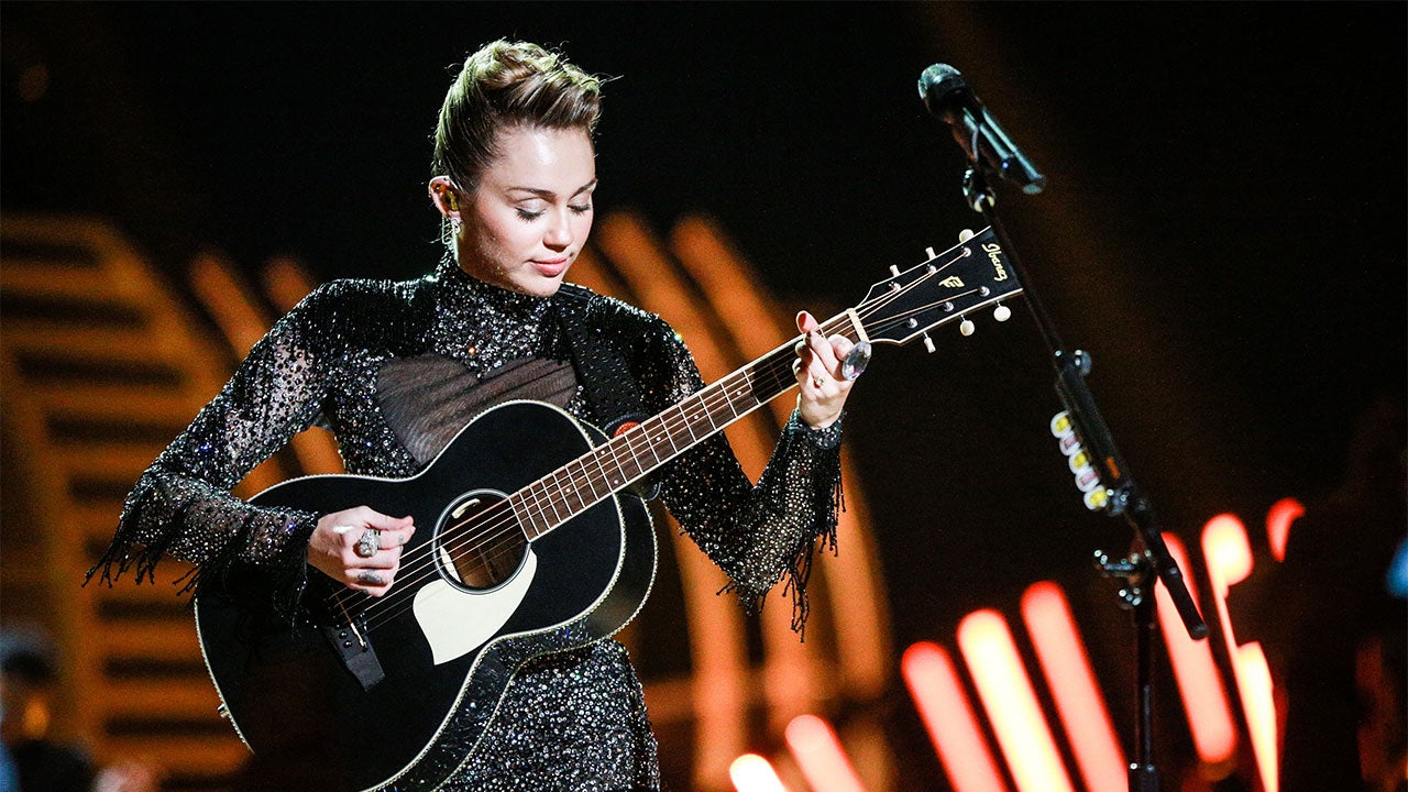Miley Cyrus on stage playing the guitar
