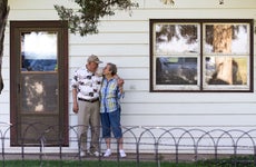 Older couple stand in front of house