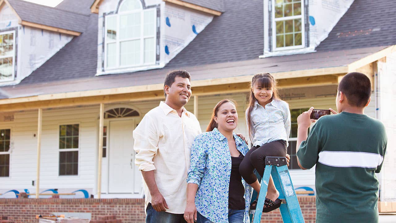 Young family posing in front of new home